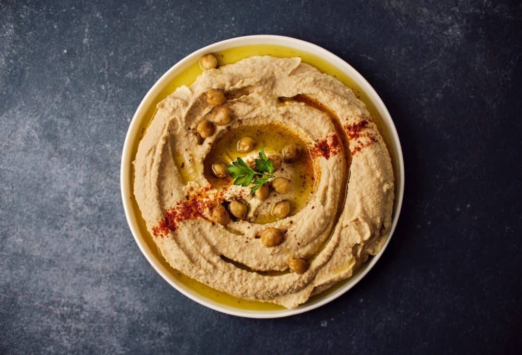 a bowl of hummus with a garnish on top
